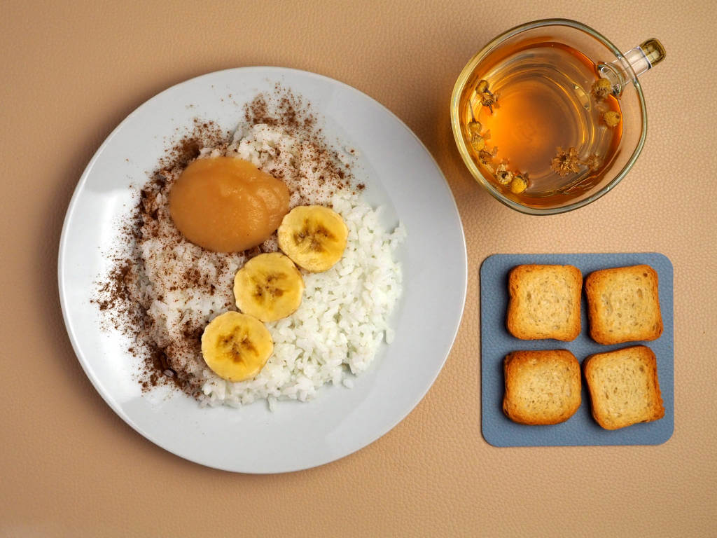 BRAT diet recipes -Toasts, white rice porridge with water, banana slices, applesauce, cinnamon powder, and camomille infusion