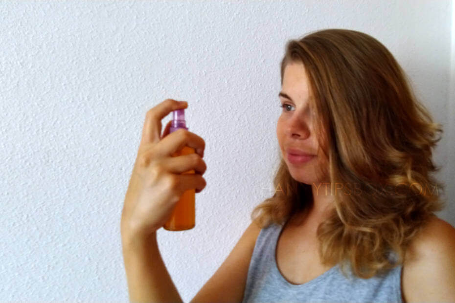A young woman is applying facial toner to her face